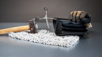 Foto-Stilleben: ein Hammer, eine Coiffeur-Schere, ein Putzlappen, ein Arbeitshandschuh und ein leeres Portemonnaie