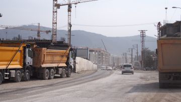 Lastwagen und Baukräne entlang einer staubigen Strasse in Antakya