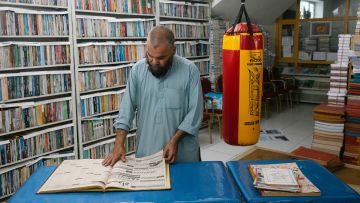 Ahmad Schah Wahdat steht an einem Tisch im Archiv-Keller und liest in einer alten Zeitung