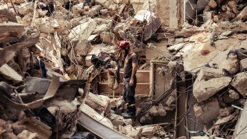 ein Helfer mit Helm steht auf den Trümmern des zerstörten Hauses in Beirut