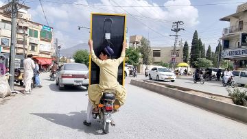 Motorradfahrer transportieren ein Solarpanel durch die Stadt Quetta