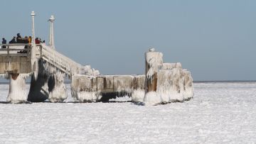 Menschen auf einem vereisten Anlegesteg auf der Insel Usedom im Jahr 2021