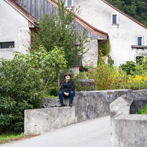 Köbi Gantenbein sitzt auf einer Mauer zwischen alten Häusern