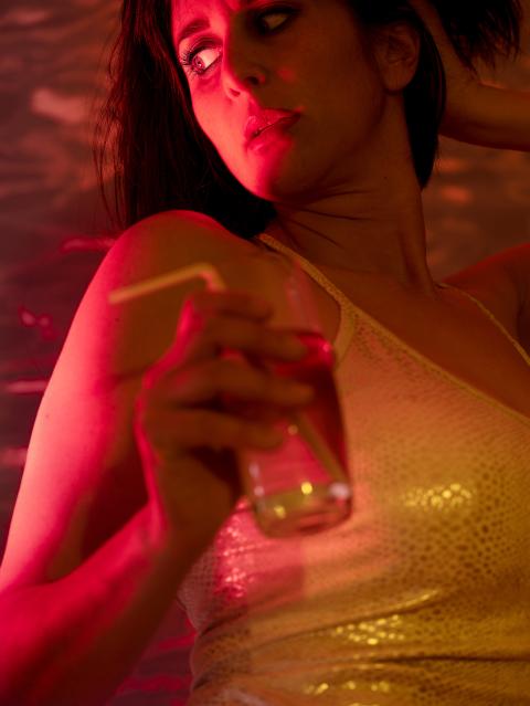 Selbstportrait-Inszenierung von Nora Rupp: Sie hält ein Glas mit Trinkröhrchen in der Hand und schaut mit skeptischen Blick nach hinten