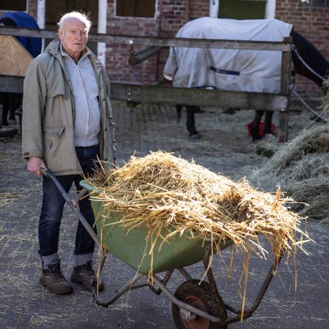 Onno Poppinga schiebt eine Schubkarre voller Stroh