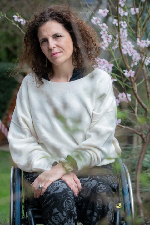 Elena Thut sitzt im Garten in ihrem Rollstuhl