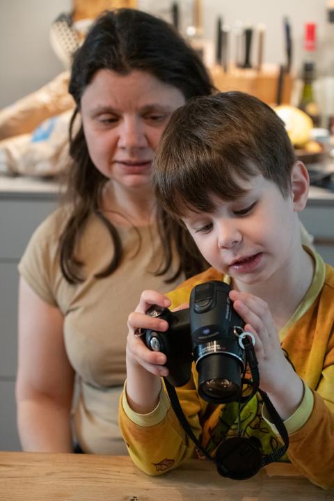 Ursulina Hermann mit Sohn, welcher eine Fotokamera bedient