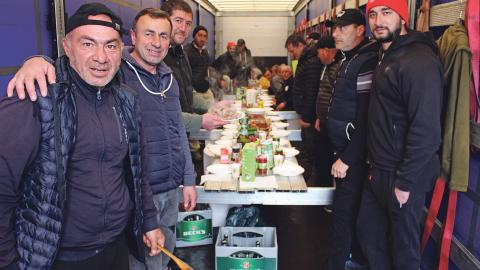 Lastwagen-Chauffeure feiern das Osterfest an einem improvisierten Tisch in einem Lastwagenanhänger