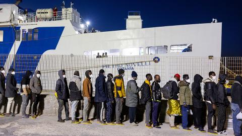 Flüchtende warten vor einem Schiff auf den Transfer nach Sizilien von der Insel Lampedusa