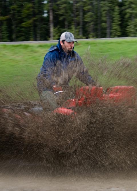 Symbolbild: ein Mann auf einem Quad-Fahrzeug im Schlamm