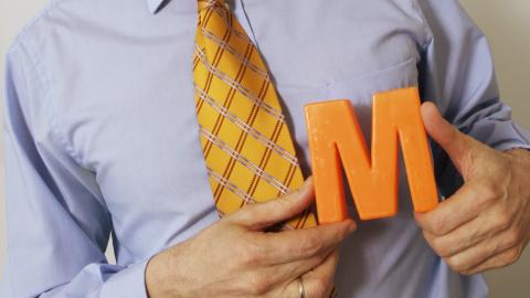 eine Person hät ein oranges Migros-M in den Händen