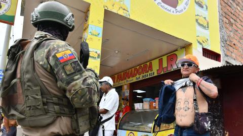 ein Armeeangehöriger mit Sturmgewehr kontrolliert Passanten auf verborgene Waffen