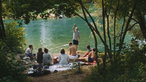 Filmstill aus «Füür brännt»: eine Gruppe Jugendlicher an einem Fluss