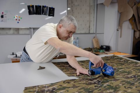 ein Hel­fer schneidert Uniformen