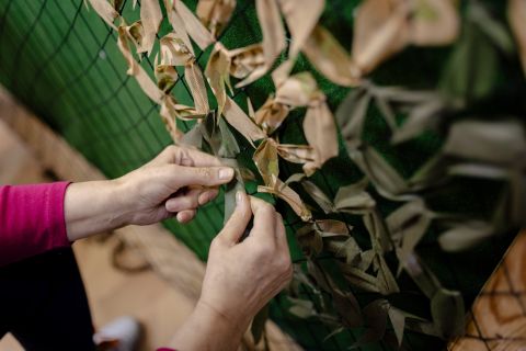 eine Hel­ferin knüpft ein Tarnnetz