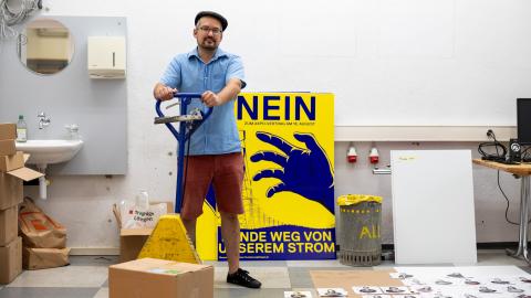 Matthias Frick steht vor einem Abstimmungs-Plakat