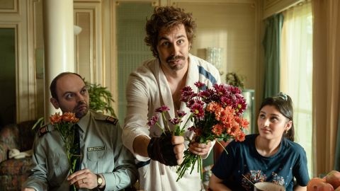 Filmstill aus der Filmfassung von «Tschugger»: David Constantin als Polizist Bax überreicht einen Blumenstraus