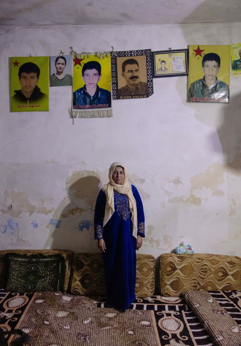 Hawar Barawad steht vor einer Wand mit Portaits von gefallenen kurdischen Kämpfer:innen