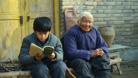 Filmstill aus «Living the Land»: der zehnjährige Chuang sitzt mit einer alten Frau auf einer Bank