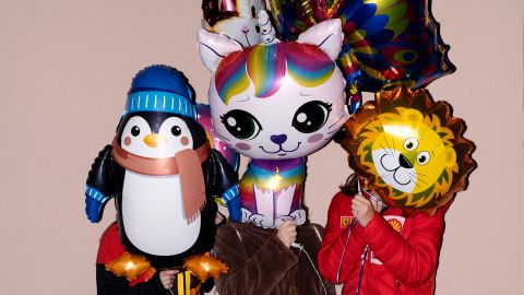 3 Personen halten sich Fantasiefiguren-Luftballons vors Gesicht
