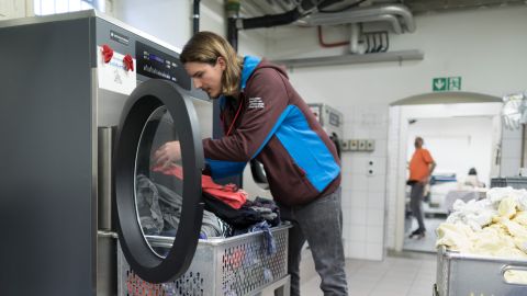 Symbolbild: ein Zivildienstleistender befüllt eine grosse Waschmaschine mit Wäsche