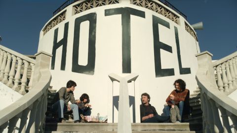 Filmstill aus «Hôtel Silence»: mehrere Personen sitzen auf einer Treppe