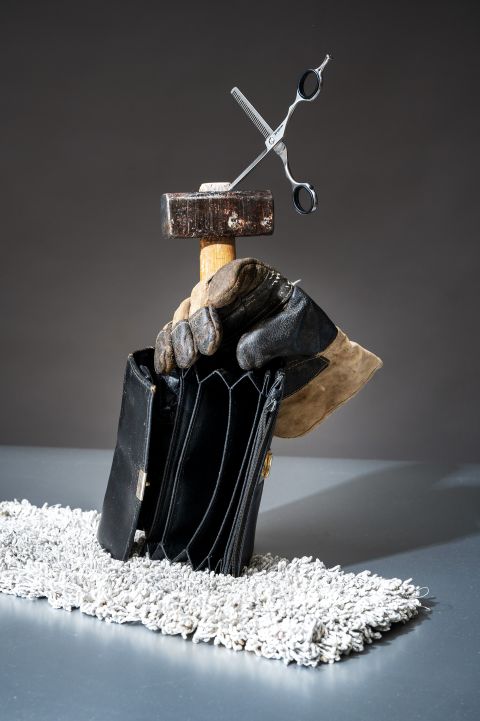 Foto-Stilleben: ein Hammer, eine Coiffeur-Schere, ein Putzlappen, ein Arbeitshandschuh und ein leeres Portemonnaie