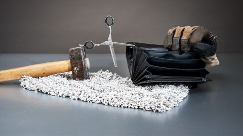 Foto-Stilleben: ein Hammer, eine Coiffeur-Schere, ein Putzlappen, ein Arbeitshandschuh und ein leeres Portemonnaie