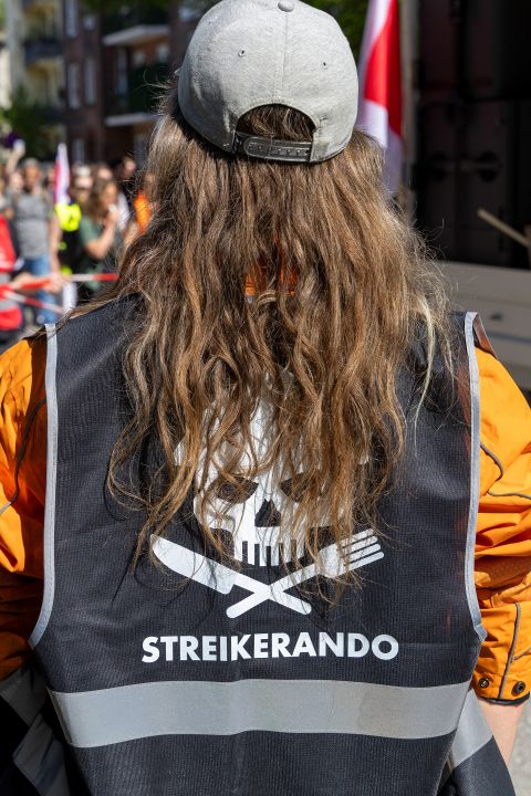 Lieferando-Rider trägt ein Gillet mit dem Aufdruck «Streikerando» an der 1.-Mai-Demo in Hamburg