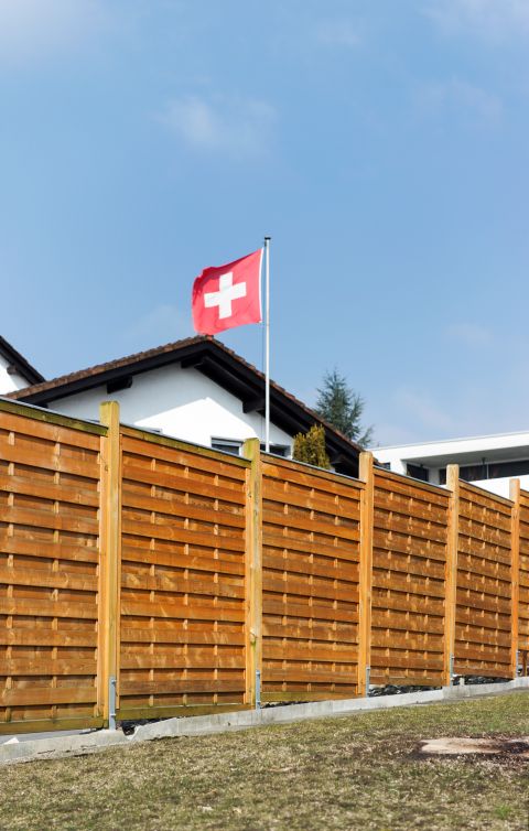 Symbolbild: Holzzaun vor einem Einfamilienhaus