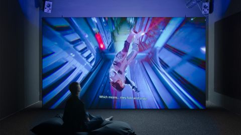 Projektion von Ayoung Kims Video «Delivery Dancer’s ­Sphere» an eine Wand, davor sitzt eine Person am Boden