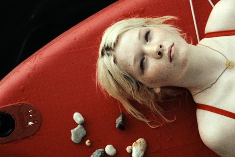 Filmstill aus «In die Sonne schauen»: eine junge Frau liegt auf einem SUP-Brett