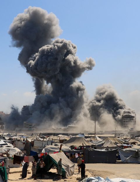 vertriebene Palästinenser:innen in einem Zeltlager Mitte September in Gaza-Stadt, im Hintergrund Staubwolken eines Bombardement