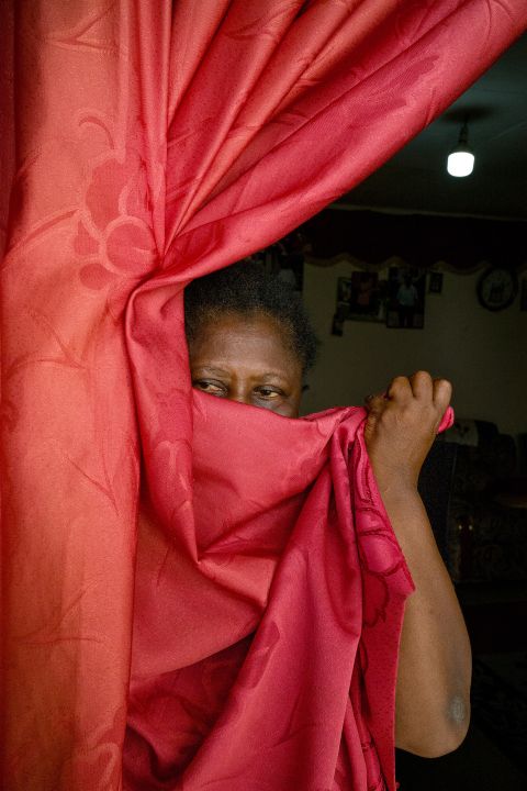 Marie Mamfe verdeckt ihr Gesicht mit einem Vorhang