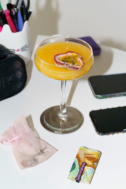 Stilleben auf einem Tisch: ein Cocktail, Schmuck, Smartphones und Bargeld