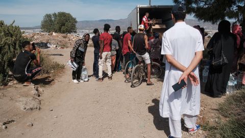 Migrantische Arbeiter:innen warten vor einem Lastwagen auf Hilfsgüter