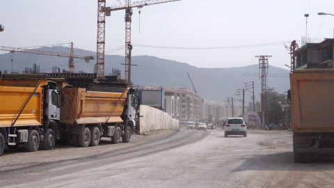 Lastwagen und Baukräne entlang einer staubigen Strasse in Antakya