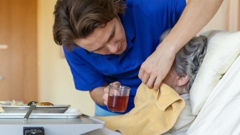 Symbolbild: eine Pflegefachperson gibt einer älteren Person zu trinken