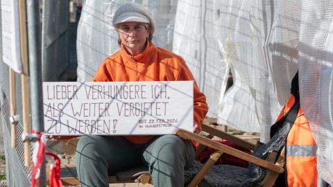 Silvia Horrer zeigt ein Schild mit der Aufschrift «LIEBER VERHUNGERE ICH. ALS WEITER VERGIFTET ZU WERDEN! SEIT 22. FЕB. 2026 IM HUNGERSTREIK»