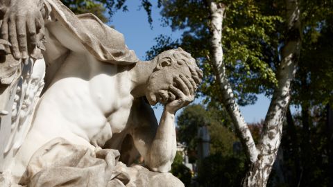Skulptur auf dem Wiener Zentralfriedhof: ein Mann stützt seinen Kopf auf seiner Hand ab