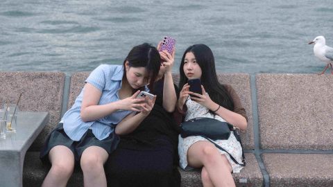 junge Australierinnen in Sydney schauen auf ihre Smartphones