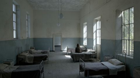 Filmstill aus «Lydia. Aufzeichnungen aus dem Irrenhaus»: Schlafsaal einer psychiatrischen Klinik, auf einem Bett sitzt eine Person