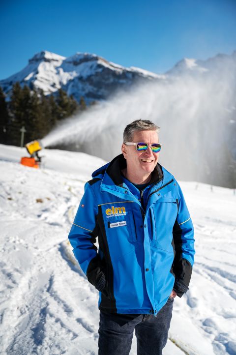 Stefan Elmer steht im Skigebiet vor einer aktiven Schneekanone