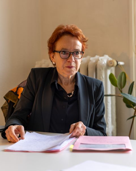 Eva Herzog sitzt mit Unterlagen an einem Tisch