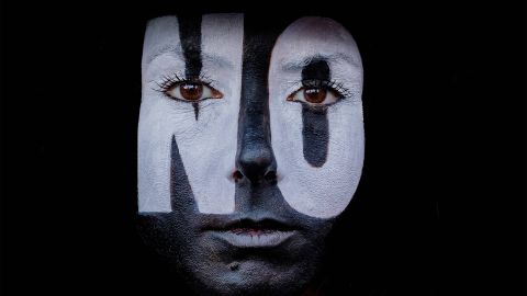 ein schwarz geschminktes Gesicht mit weissen Buchstaben NO