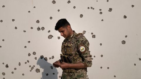 Portraitfoto von Saman in Kampfmontur vor einer Wand mit Einschusslöchern