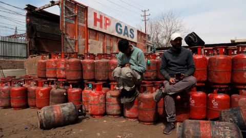 zwei Männer sitzten bei einem Lager mit leeren Gasflaschen
