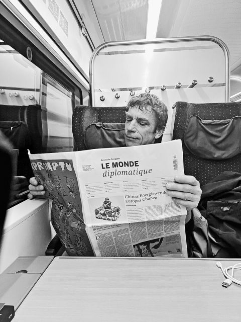 eine Person liest den «Le Monde diplomatique» im Zug