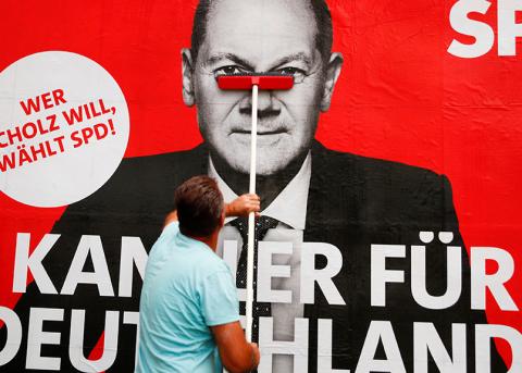 Plakatierer hängt ein SPD-Plakat mit Olaf Scholz auf