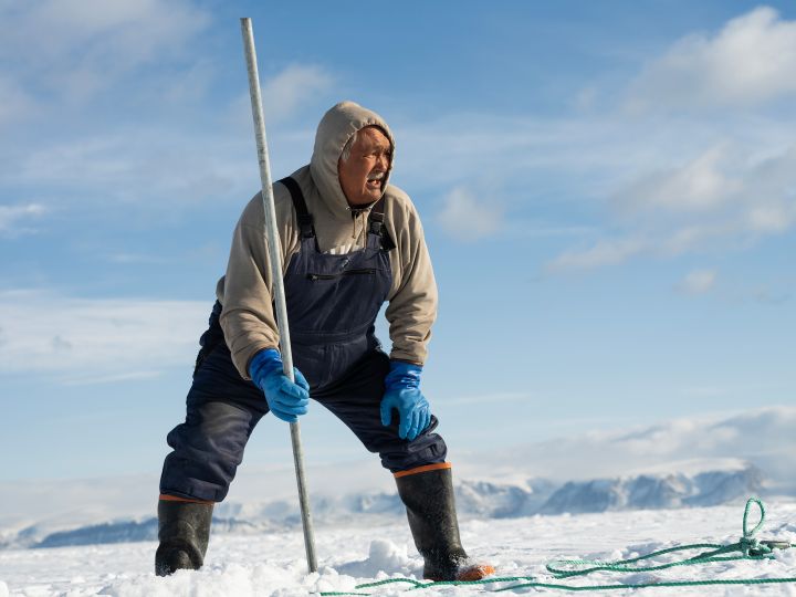 Jäger Mamarut Kristiansen befestigt sein Boot mit einem Seil und Stab im Eis